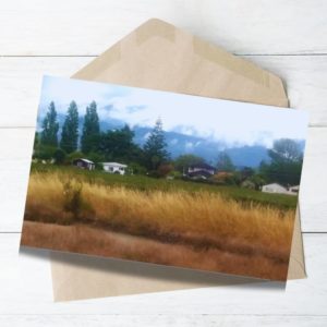 Beautiful nz landscape yellow grass, green tress blue mountain and houses in the valley.